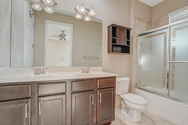 full bathroom featuring combined bath / shower with glass door, vanity, ceiling fan, toilet, and tile patterned floors