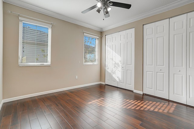 unfurnished bedroom featuring multiple closets, crown molding, dark hardwood / wood-style floors, and ceiling fan