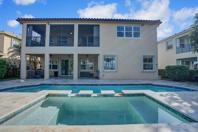 rear view of property with a swimming pool with hot tub, a patio, and a balcony