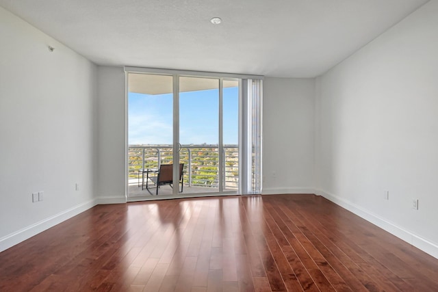 spare room with dark hardwood / wood-style flooring and floor to ceiling windows