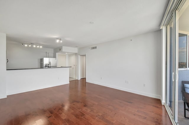 unfurnished living room with plenty of natural light and dark hardwood / wood-style flooring