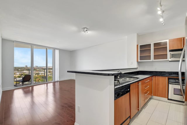 kitchen featuring stainless steel appliances, floor to ceiling windows, kitchen peninsula, and sink