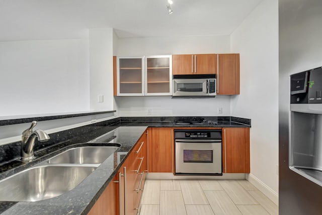 kitchen with sink, stainless steel appliances, and dark stone countertops