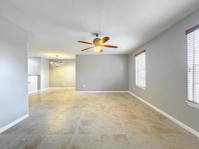 tiled spare room featuring ceiling fan with notable chandelier and a textured ceiling