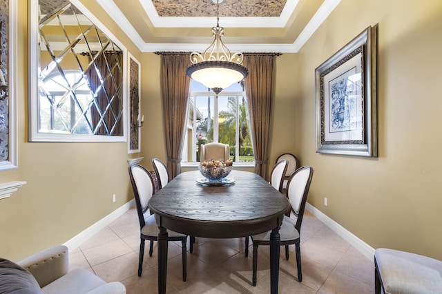 tiled dining space featuring crown molding and a tray ceiling