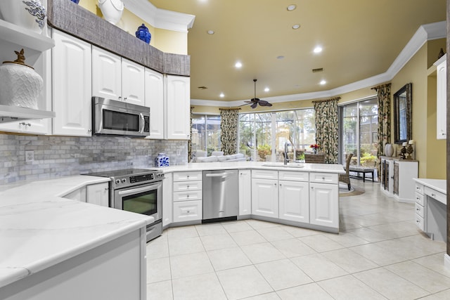 kitchen with tasteful backsplash, kitchen peninsula, sink, appliances with stainless steel finishes, and white cabinets