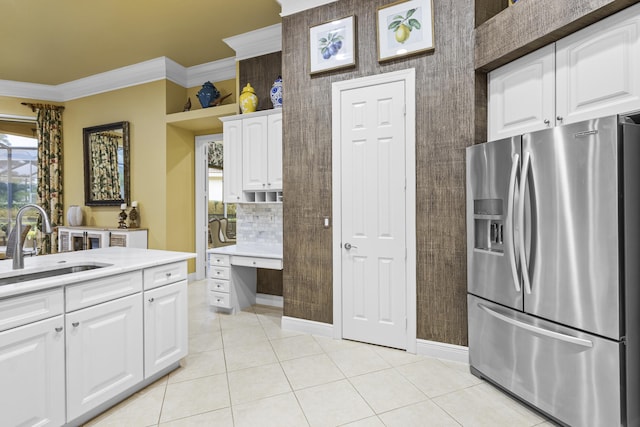 kitchen with decorative backsplash, sink, white cabinetry, ornamental molding, and stainless steel fridge