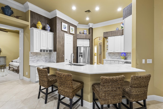 kitchen with white cabinets, a kitchen bar, kitchen peninsula, and sink