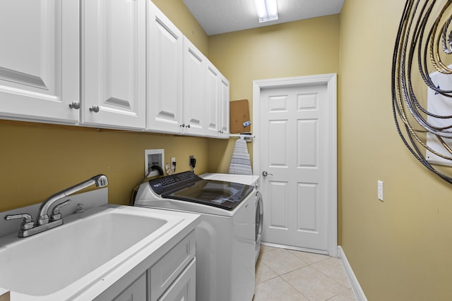 clothes washing area featuring sink, washer and clothes dryer, a textured ceiling, light tile patterned floors, and cabinets