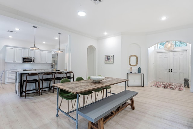 dining room featuring sink, crown molding, and light hardwood / wood-style flooring