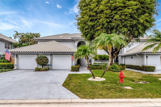 view of front facade with a front yard, driveway, stucco siding, a garage, and a tile roof