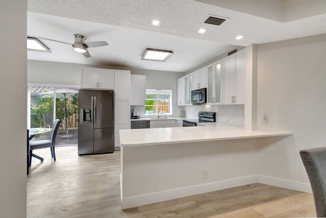 kitchen with stainless steel electric range oven, visible vents, light countertops, black microwave, and refrigerator with ice dispenser