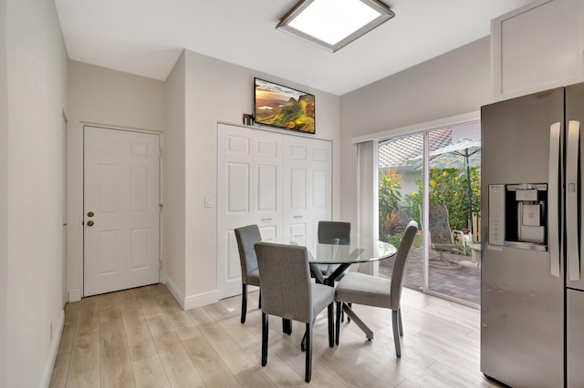 dining space featuring light wood-style flooring and baseboards