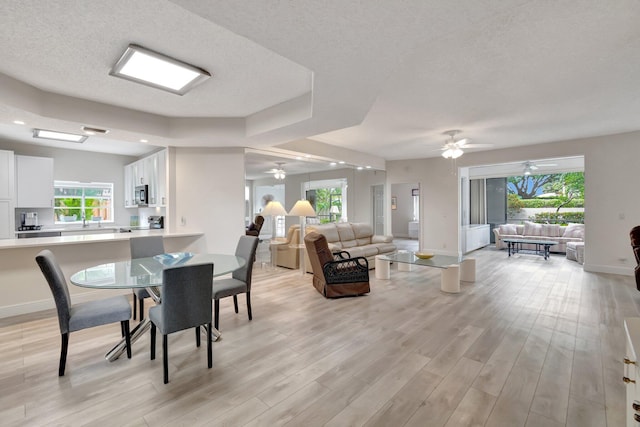 dining space featuring a wealth of natural light, baseboards, a textured ceiling, and light wood-style floors