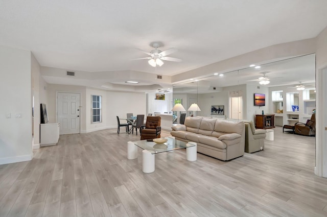 living area with light wood finished floors, visible vents, and baseboards