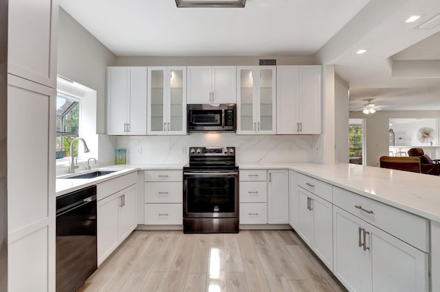 kitchen featuring a wealth of natural light, a sink, backsplash, stainless steel appliances, and white cabinets