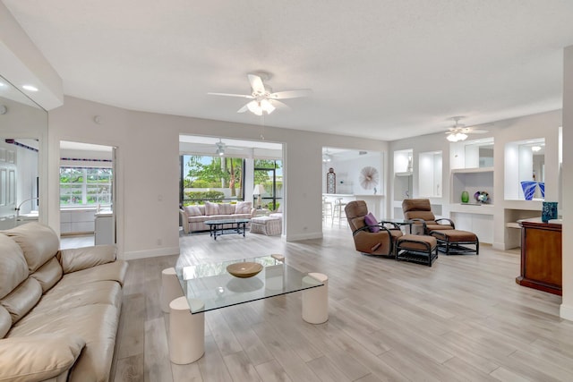 living room featuring plenty of natural light, light wood-type flooring, baseboards, and built in features