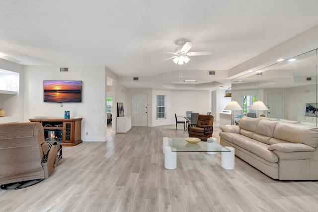 living area with light wood-type flooring, visible vents, baseboards, and a ceiling fan