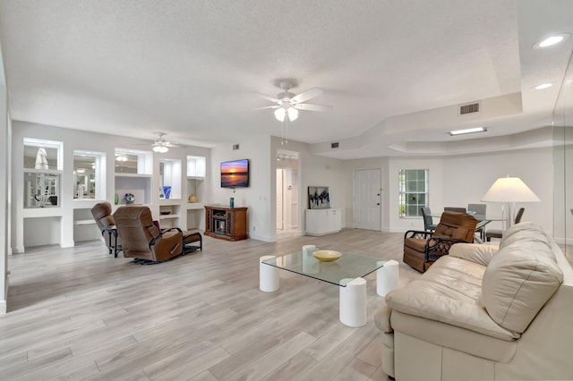 living area featuring visible vents, light wood-style flooring, recessed lighting, ceiling fan, and a textured ceiling