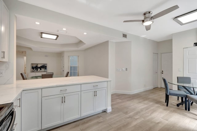 kitchen with light stone counters, light wood-style floors, stainless steel electric range, a peninsula, and baseboards