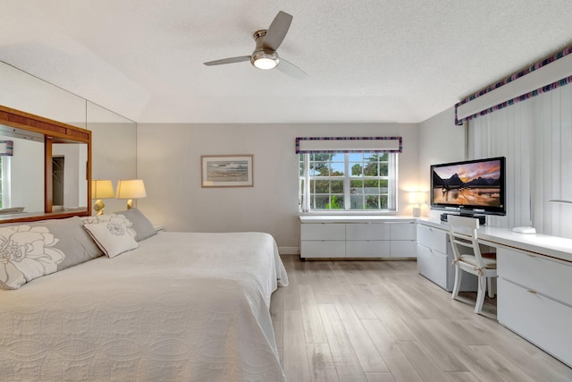 bedroom with light wood-style flooring, a textured ceiling, built in study area, and ceiling fan