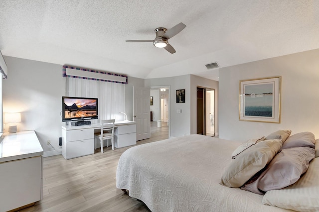 bedroom featuring visible vents, light wood-style flooring, ceiling fan, vaulted ceiling, and a textured ceiling