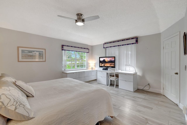 bedroom with light wood finished floors, a textured ceiling, baseboards, and a ceiling fan