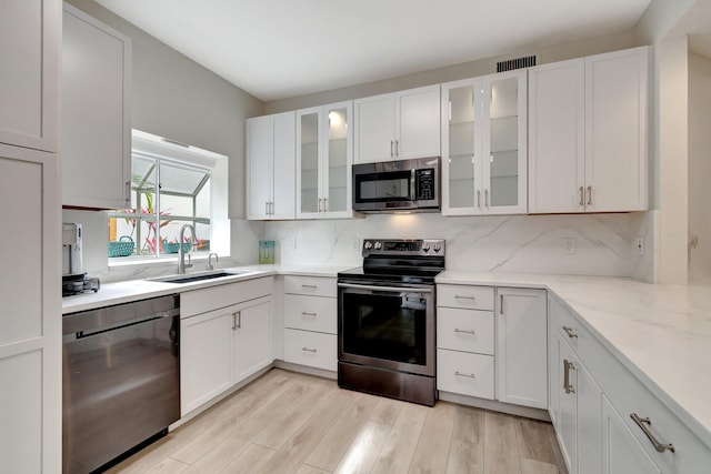 kitchen featuring a sink, decorative backsplash, appliances with stainless steel finishes, and white cabinets