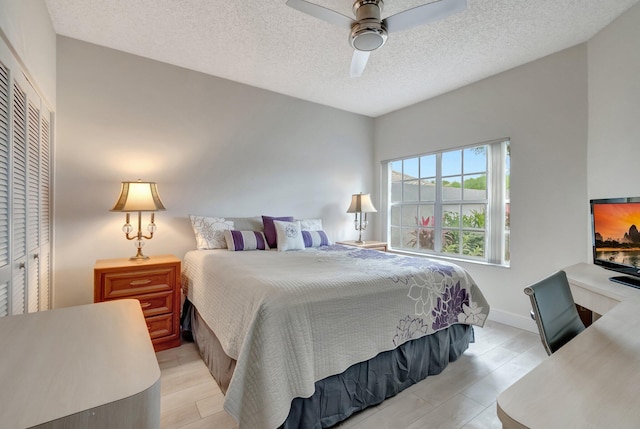 bedroom featuring ceiling fan, light wood-style flooring, baseboards, and a textured ceiling