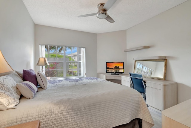 bedroom featuring a ceiling fan, wood finished floors, and a textured ceiling