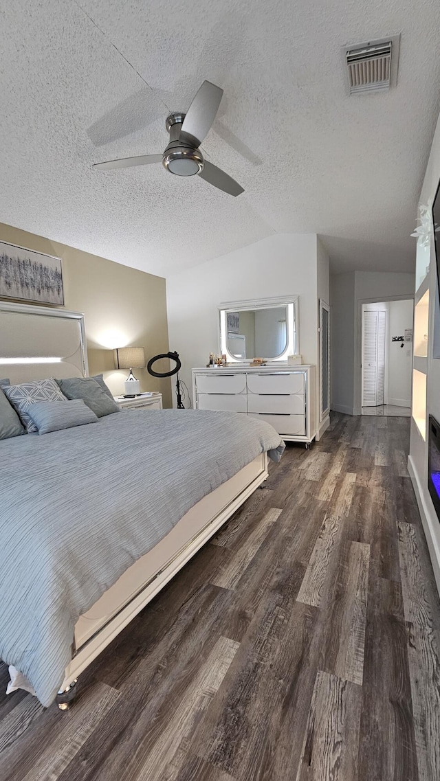 unfurnished bedroom featuring ceiling fan, dark hardwood / wood-style floors, vaulted ceiling, and a textured ceiling