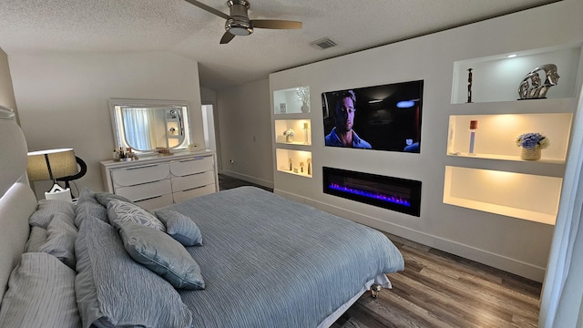 bedroom with vaulted ceiling, a textured ceiling, ceiling fan, and wood-type flooring