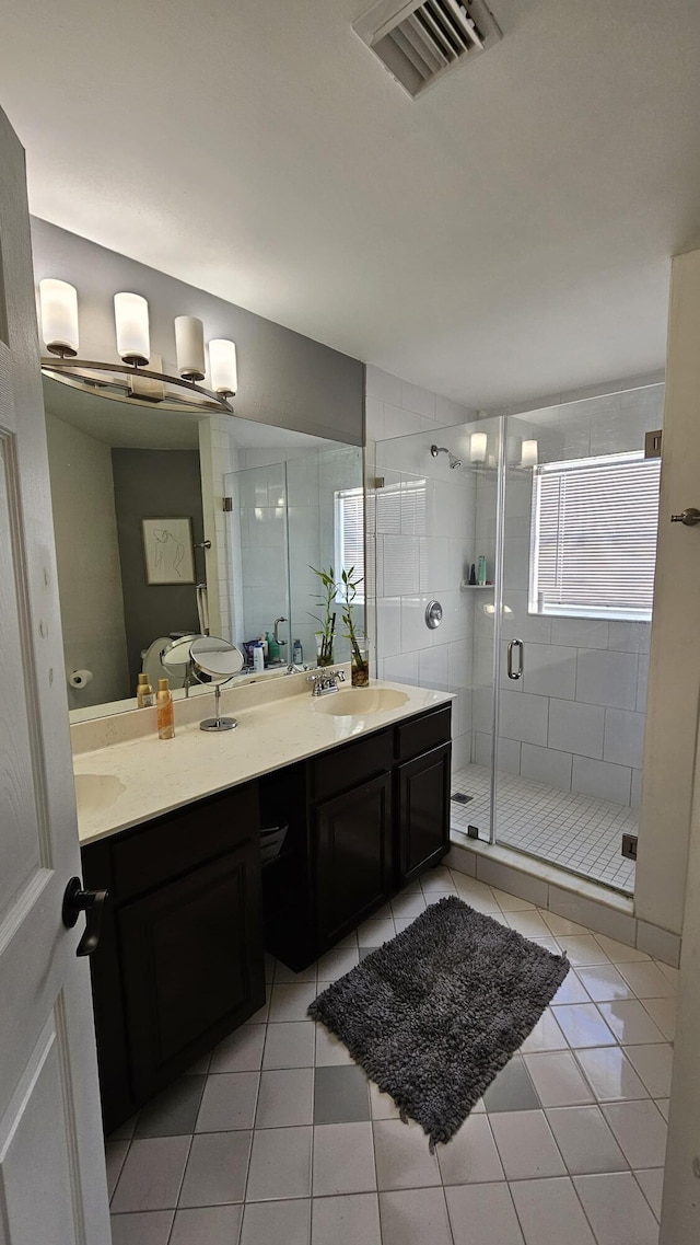 bathroom with tile patterned flooring, a shower with shower door, and vanity