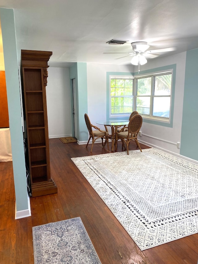 sitting room with ceiling fan and dark wood-type flooring