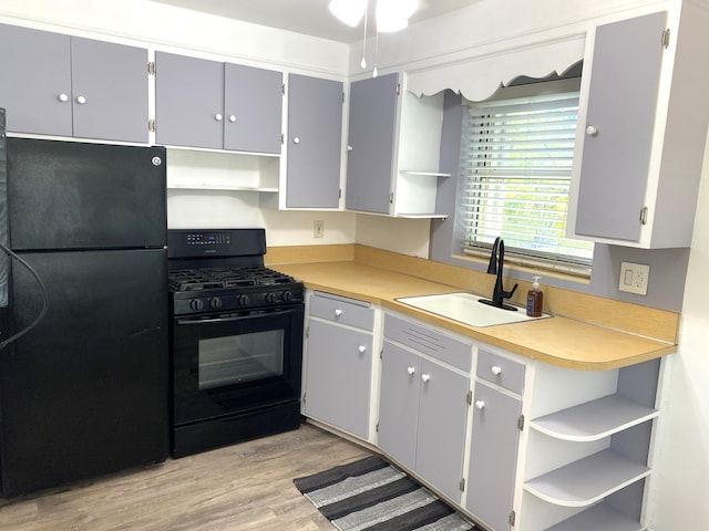 kitchen featuring black appliances, sink, gray cabinets, and light hardwood / wood-style floors