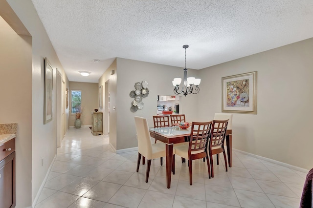 dining area with a textured ceiling, an inviting chandelier, and light tile patterned floors