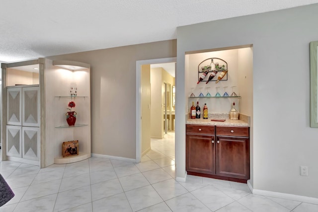 hall featuring a textured ceiling and light tile patterned floors