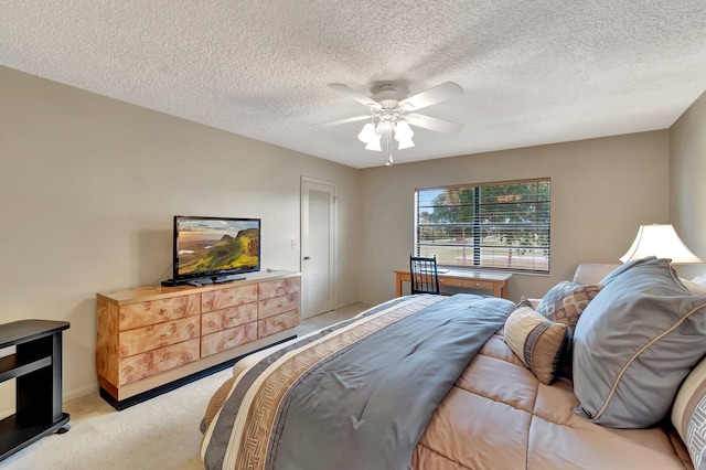 bedroom with ceiling fan, light colored carpet, and a textured ceiling