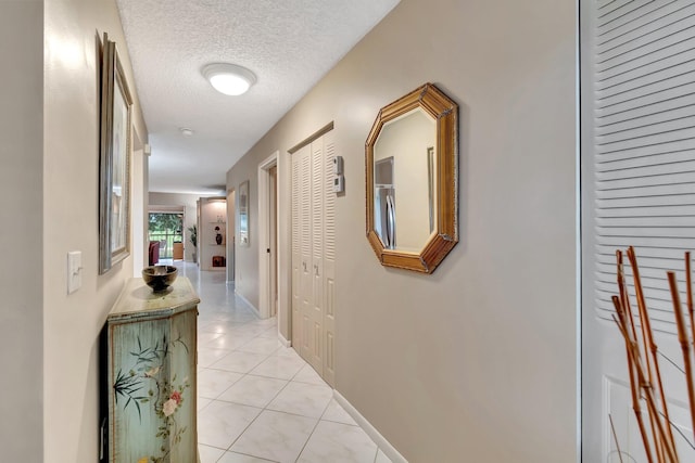 hallway with a textured ceiling and light tile patterned floors