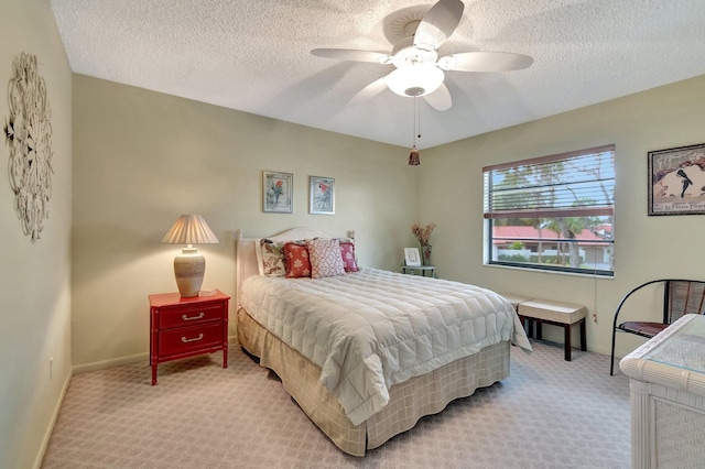 bedroom featuring ceiling fan, light colored carpet, and a textured ceiling