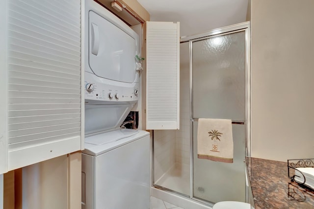 laundry area featuring stacked washing maching and dryer and light tile patterned floors