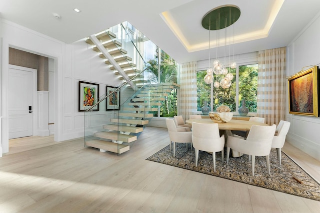 dining space featuring a tray ceiling, light hardwood / wood-style floors, and a chandelier