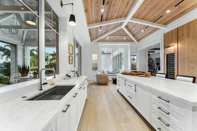 kitchen featuring light stone countertops, white cabinetry, wooden ceiling, and sink