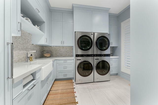 clothes washing area featuring stacked washer and dryer, cabinets, washer and clothes dryer, and sink