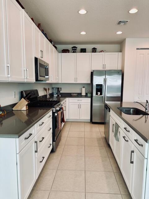 kitchen with appliances with stainless steel finishes, white cabinets, and sink