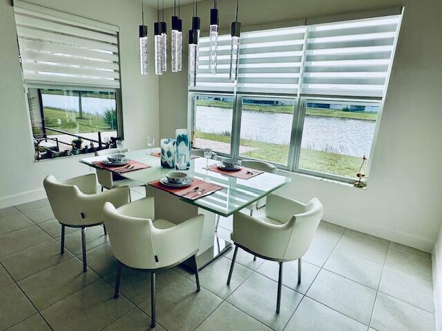 dining area with a water view and tile patterned floors