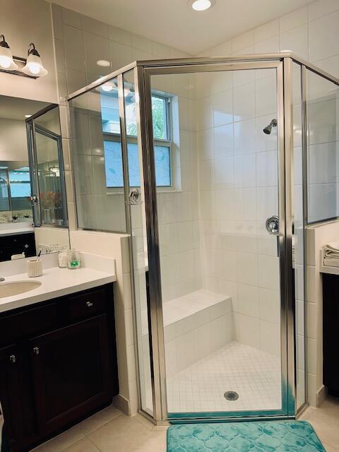 bathroom with a shower with shower door, vanity, and tile patterned floors