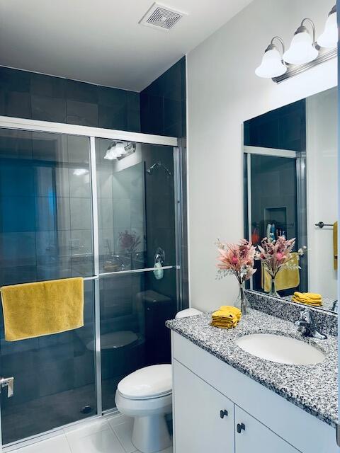 bathroom featuring toilet, a shower with door, tile patterned floors, and vanity