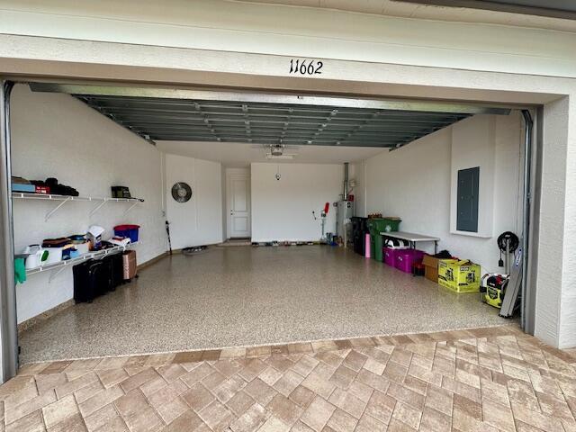 garage featuring water heater, a garage door opener, and electric panel