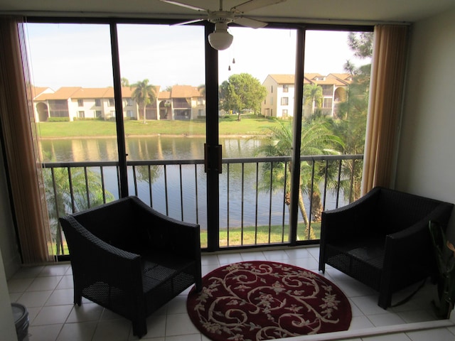 sunroom with ceiling fan and a water view